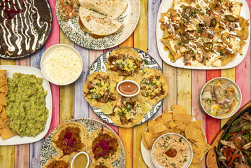 Plate set with Mexican food recipes with tacos of all kinds on wheat and corn tortillas, quesadillas, wire stew, ceviche, grated cheese and colored table