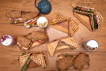 Set of snacks, sandwiches and drinks on a wooden table.