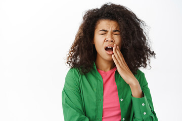 Fototapeta na wymiar Tired african american woman yawning, feels tired, covers opened mouth with hand, being bored, standing over white background