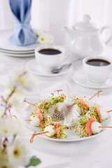 Appetizer quail egg stuffed with alfalfa sprouts with a slice of salmon, on a wooden skewer. Buffet serving for the Easter table.
