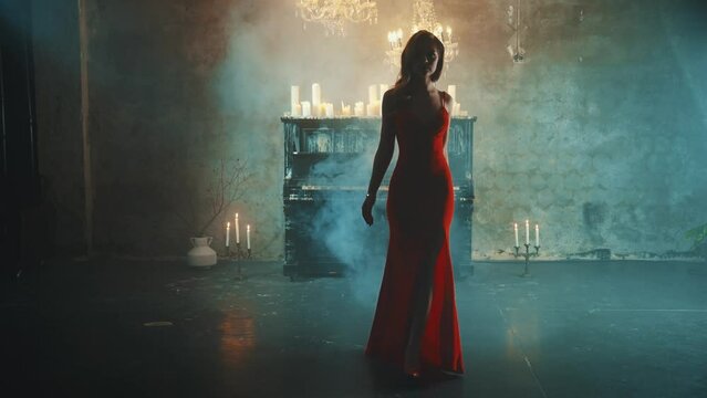 Dark Silhouette fantasy lady gothic beautiful woman blond hair in red dress walks in luxurious room black piano candles light burn. Evening dress slit on long leg fashion model sexy girl vampire queen