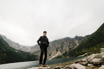 A man stand on the stony shore of the Sea Eye lake in Poland. Scenic mountain view. Morskie Oko. Tatra mountains.