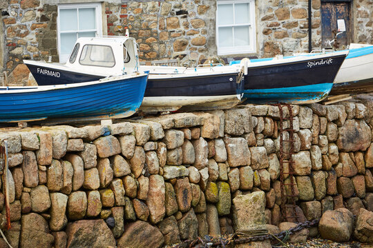 Mousehole, Cornwall, UK - Port wall with fishing boats on top at low tide