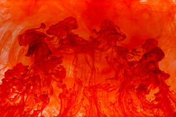 Red paint dissolving in water creating abstract shapes	