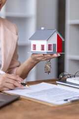 Business Asian woman working with House model real estate agent and customer discussing for contract to buy house key, insurance or loan real estate consult concerning mortgage loan offer in office.
