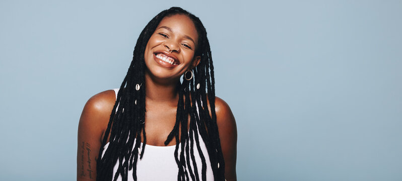 Portrait of a african woman with dreadlocks smiling at the camera in a studio