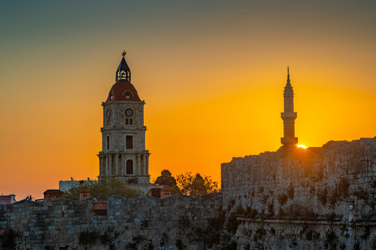 View of sunrise between Medieval Clock Tower and Mosque of Suleiman, UNESCO World Heritage Site, Rhodes Town, Rhodes, Dodecanese Island Group, Greek Islands
