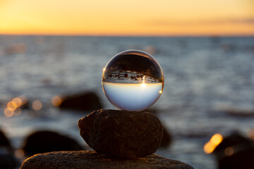 The glass ball lies on the top stone reflecting the beach and the sea