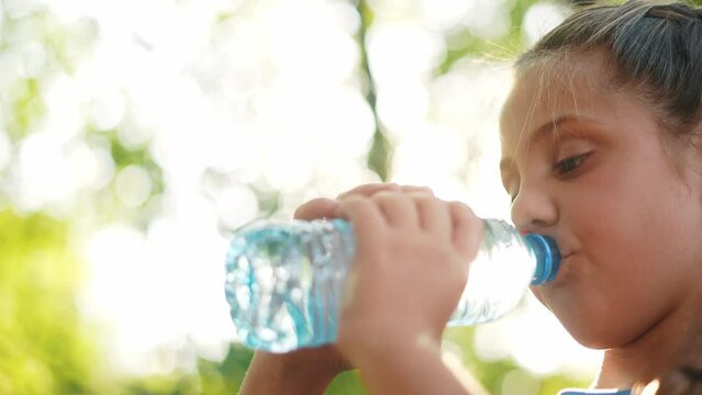 Child Drinking Water From A Plastic Bottle. Water Shortage Problem On Earth Concept. Water Shortage Problem On Earth Concept. Kid Drinks Water In Nature From A Lifestyle Bottle Glare Of The Sun Summer