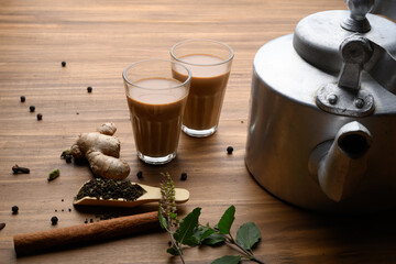 Indian chai in glass cups with metal kettle and other masalas to make the tea.