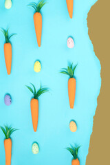 Carrot and colorful eggs on brown and blue torn paper background. Easter thema.