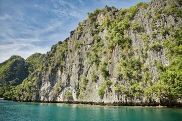 Naklejka premium Majestic rocks in Coron, Palawan in the Philippines that are overgrown with shrubs and rise out of the water.