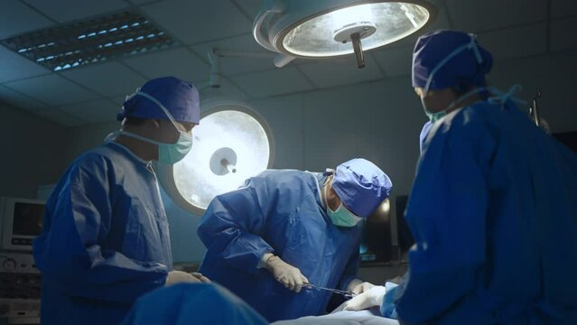 Team professional surgeons and nurses in uniform at work in operating room,performing heart transplant surgery operation under bright lamps and looking at screen.Teamwork surgeon in operating room