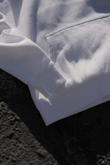 Fototapeta na wymiar MOKITUP: Lifestyle Isolated Folded Raglan Sleeve Hoody Mockup on Beachside in sand and Rocks 