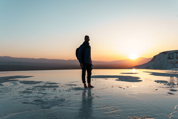 Fototapeta premium Traveller man with backpack in Pamukkale in the middle of sunset in travertines