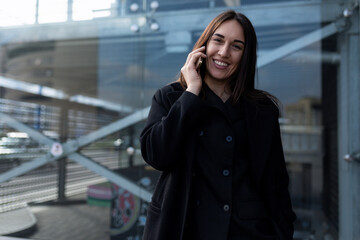 Fototapeta premium european business woman talking on the phone against the backdrop of a city office building