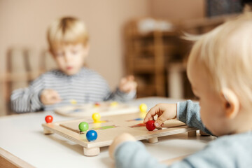Selective focus on a little boy playing with interactive montessori toy and learning colors.