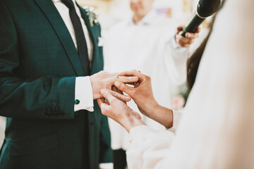 Zakładanie obrączek ślubnych w kościele. Para Młoda podczas ślubu © Image-Love