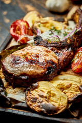 Pork steak on the bone, barbecued with vegetables on a wooden board. Close up