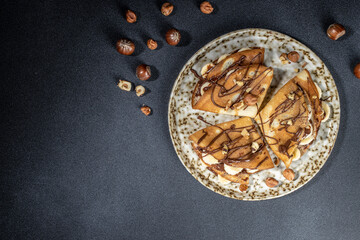 Homemade thin crepes with chocolate spread, banana and hazelnuts. breakfast or dessert. banner, menu, recipe place for text, top view