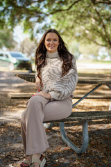 Beautiful young female model posing in the park in the animal print sweater