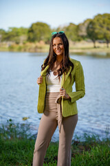 Beautiful young female model posing in a green jacket in a nature seen in the park
