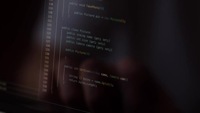 Close-up of a computer screen with lines of program code. The programmer will scroll through the code to look for bugs and errors.