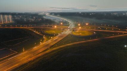Aerial view of the bigger traffic interchange with many cars next to forest and the historical and...
