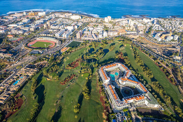 Aerial view above golf course surrounded by villas, condos and resort in Playa las Americas, Tenerife, Canary Islands Spain