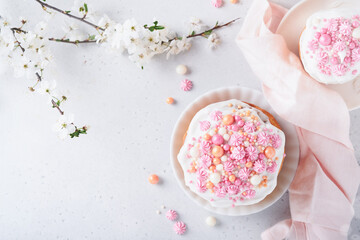 Fototapeta na wymiar Traditional Easter sweet bread or cakes with white icing and sugar decor, colored eggs and cherry blossom tree branch over white table. Various Spring Easter cakes. Happy Easter day. Selective focus.