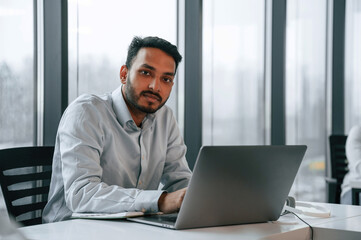 Fototapeta premium Beautiful indian man is working in the office by laptop