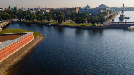Fototapeta na wymiar Aerial view of the Peter-Pavel's Fortress, Church next to bridges and Sailing ship on the river and water channel in the historical centre of city of St. Petersburg at clear summer sunrise