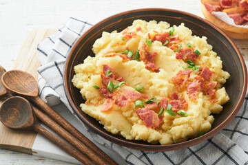 Mashed potatoes. Bacon mashed potatoes with green onion, pepper and cheddar cheese in bowl on old wooden backgrounds. Delicious creamy mashed potatoes. Top view.
