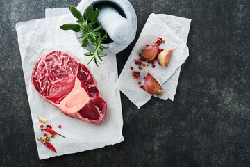 Osso Buco raw steak meat. Barbecue meat. Raw fresh cross cut veal shank and seasonings pepper, rosemary, thyme and salt on dark background. Beef Leg Slice . Italian menu. Top view.