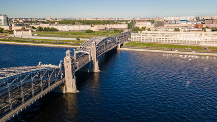 Fototapeta na wymiar Aerial above view of the car Bolsheokhtinsky bridge above the river and water channel in the historical and at same time modern centre of city of St. Petersburg at sunny summer sunset
