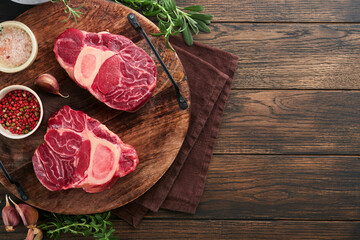 Osso Buco raw steak meat. Barbecue meat. Raw fresh cross cut veal shank and seasonings pepper, rosemary, thyme and salt on old wooden background. Beef Leg Slice with marrow. Italian menu. Top view.