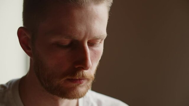 A close-up of a man with a frown looking down somewhere. An experienced programmer is focused on finding errors in the application's source code.