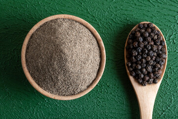 Ground black pepper with grains of black pepper on a green background,top view

