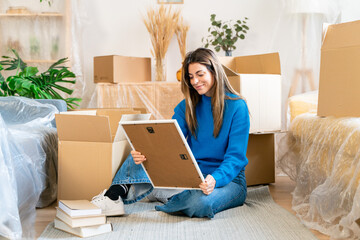 Female sitting on floor near carton boxes during relocation into new apartment