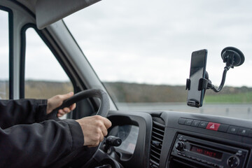man's hands on steering wheel of large van in the window attached suction cup with mobile for gps © Cristina