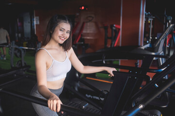 Fototapeta na wymiar A pretty woman brisk walking on the treadmill while holding on to the handlebars. Working out or doing cardio inside the gym.