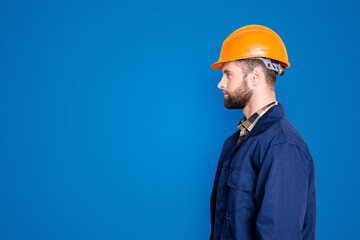 Profile side view portrait with copy space, empty place for advertisement product of virile harsh repairer in blue uniform, standing over grey background