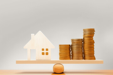 Wooden house on stack of coins isolated
