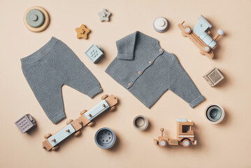 Baby stuff and accessories. Knitted clothes - cardigan, pants, shoes, toys, cubes, wooden train. Baby shower concept. Flat lay, top view. Copy space