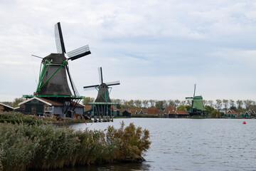 Fototapeta na wymiar Traditional Old Green Windmills along the Zaan River in Zaanse Schans Netherlands