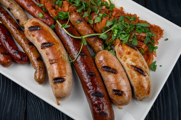 Grilled different sausage with the addition of herbs and horseradish sauce on the plate. Grilling food, bbq, barbecue concept