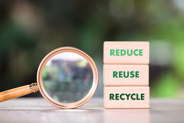 Reduce, Reuse, and Recycle text on stack wood blocks with magnifying glass, checking, focusing, meaning, concept of waste management