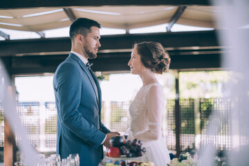 Wedding ceremony outdoors. The bride and groom hold hands, look tenderly at each other and say the oath of allegiance