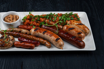 Grilled different sausage with the addition of herbs and horseradish sauce on the plate. Grilling food, bbq, barbecue concept