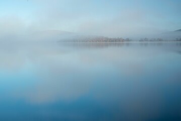Obraz premium Landscape view of the trees reflected in the sea on a foggy day